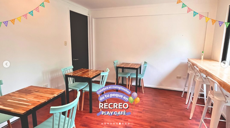 Salón de cafetería de Recreo Play Café con mesas de madera y guirnaldas